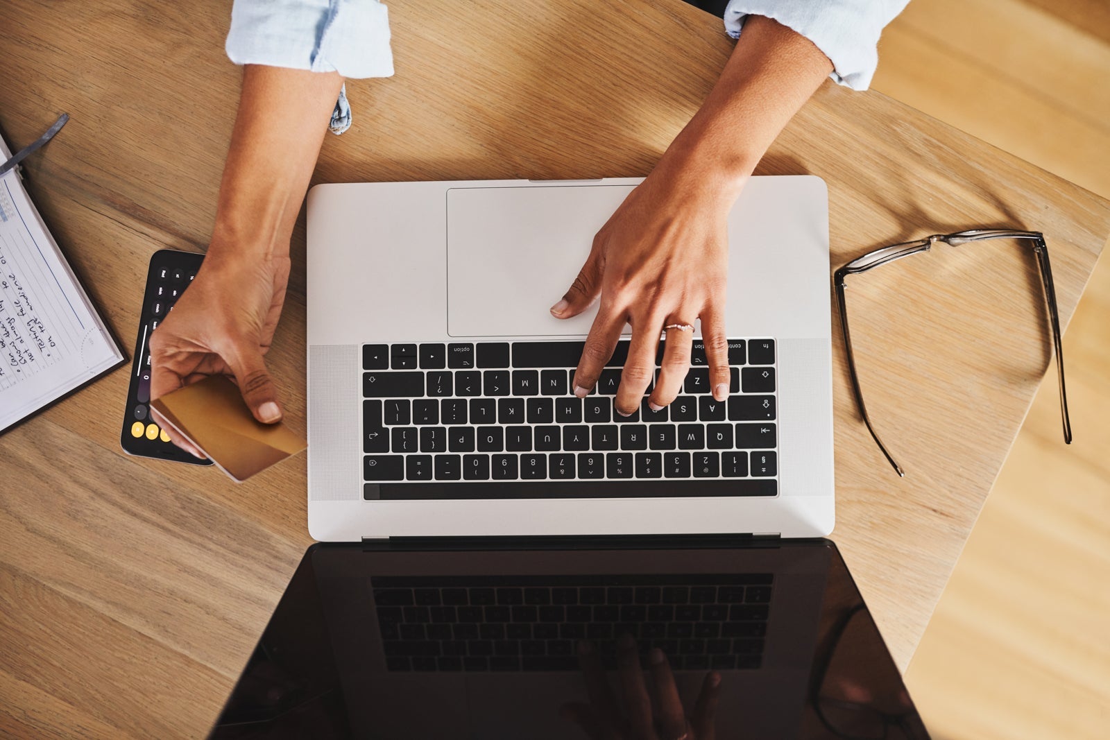 Hands hovering over a laptop with a credit card in hand