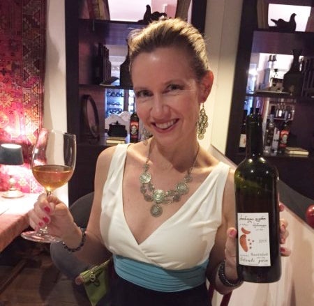 A friend of the author's sampling a glass of amber wine, something that is unique to Georgia.