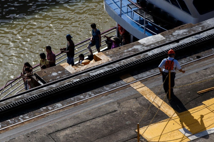Tourists ride a boat through the Miraflores locks of the Panama Canal. As the water level decreased, they were almost hidden by the walls of the canal.