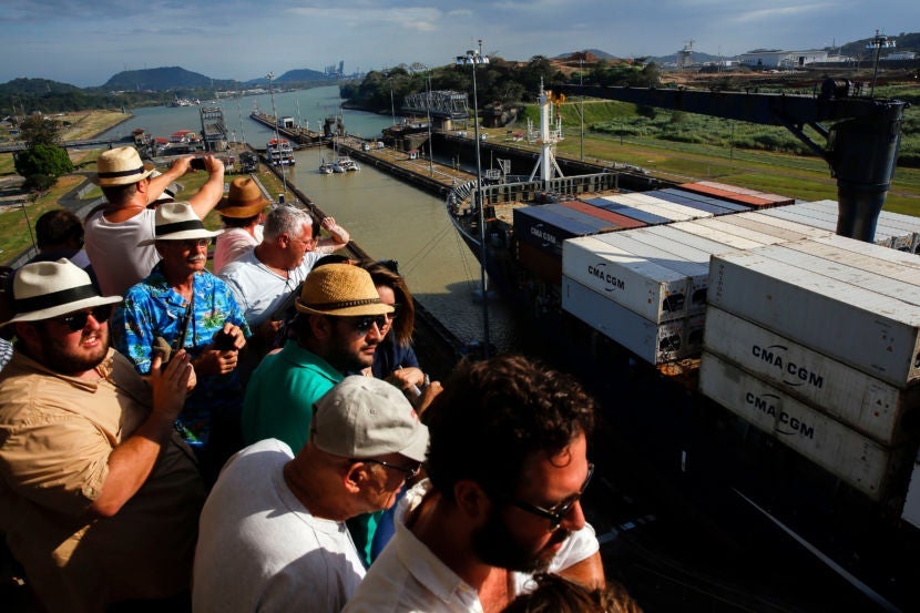 Visitors, many sporting their Panama hats, watch as a container ship passes through the Miraflores locks.