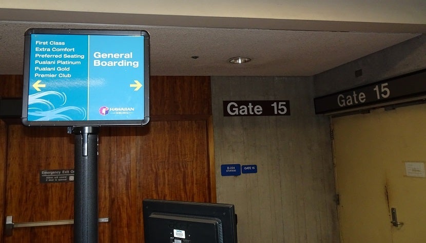 The wear and tear of Gate 15 shows behind the boarding sign.