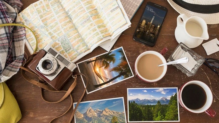 High angle view of coffee, maps, photographs, camera and cell phone