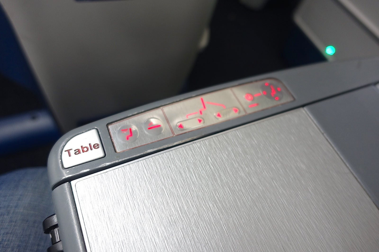 The armrest has the seat controls, table and a remote control for the entertainment system.