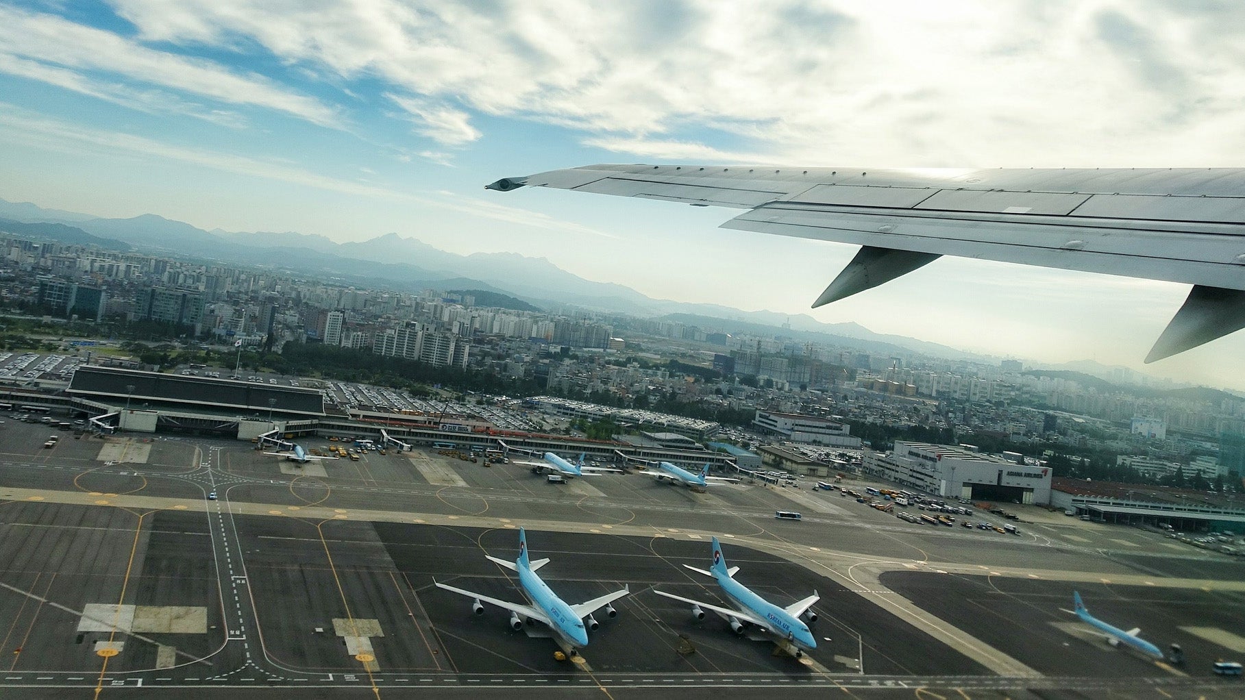 Cropped Aircraft Wings With Airplanes On Runway Against Sky