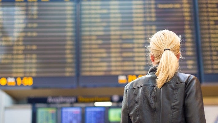 Female traveller checking flight departures board.