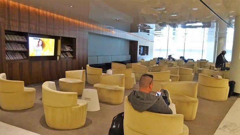 A large seating area with curvy furniture. On the left, TVs and periodicals.