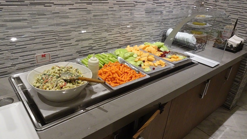 Cold and fresh, a nice selection of fruits and vegetables next to a huge bowl of pasta salad.