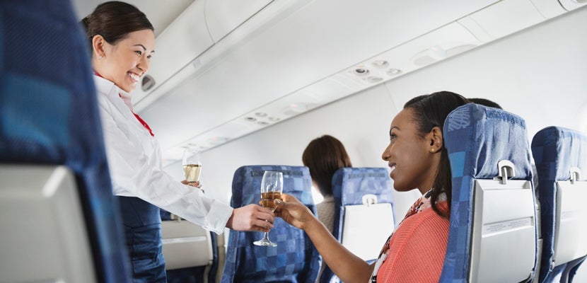 A woman having a glass of wine on an airplane. Image courtesy of Hero Images via Getty Images.
