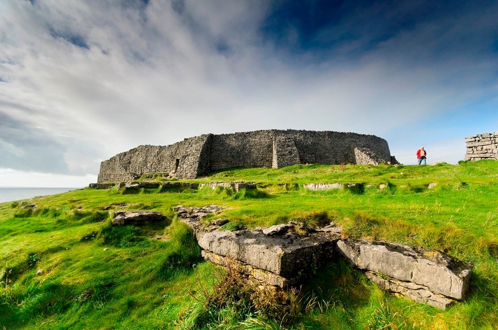 The Dún Aonghasa fortress is a striking contrast to the sea of green on the temperate island. Image courtesy of Marka via Getty Images.