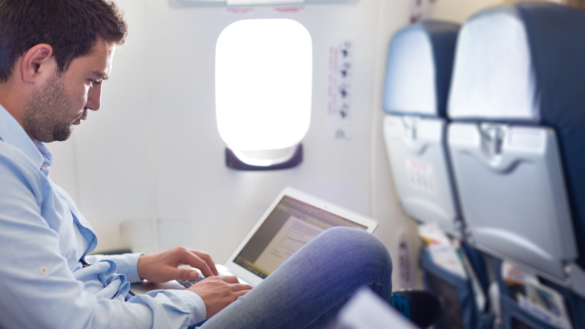 Businessman working with laptop on airplane.