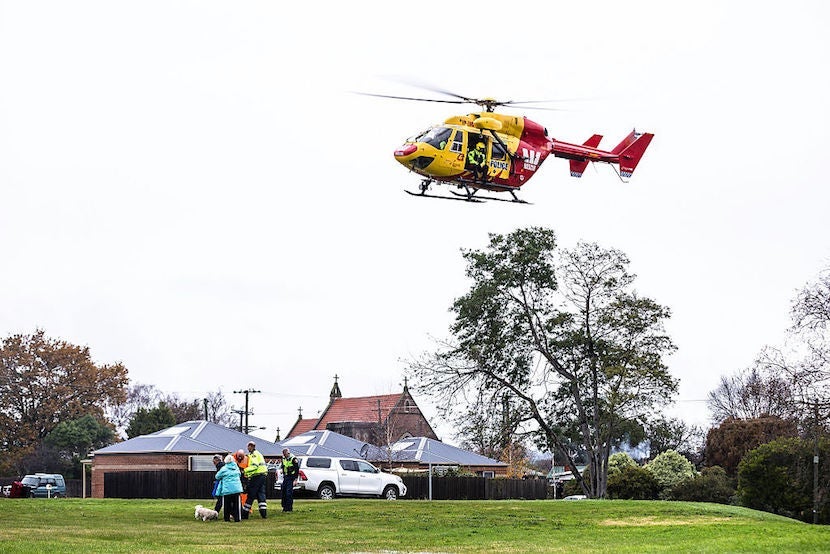a helicopter lands in a field where someone is receiving medical care