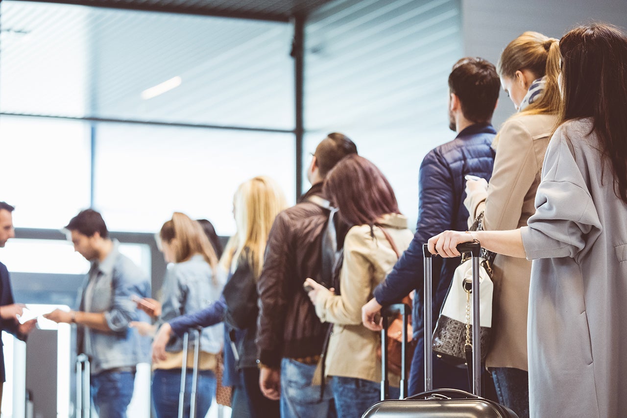 Shot of queue of passengers waiting at boarding gate at airport. Group of people standing in queue to board airplane.(Photo by izusek/Getty Images)