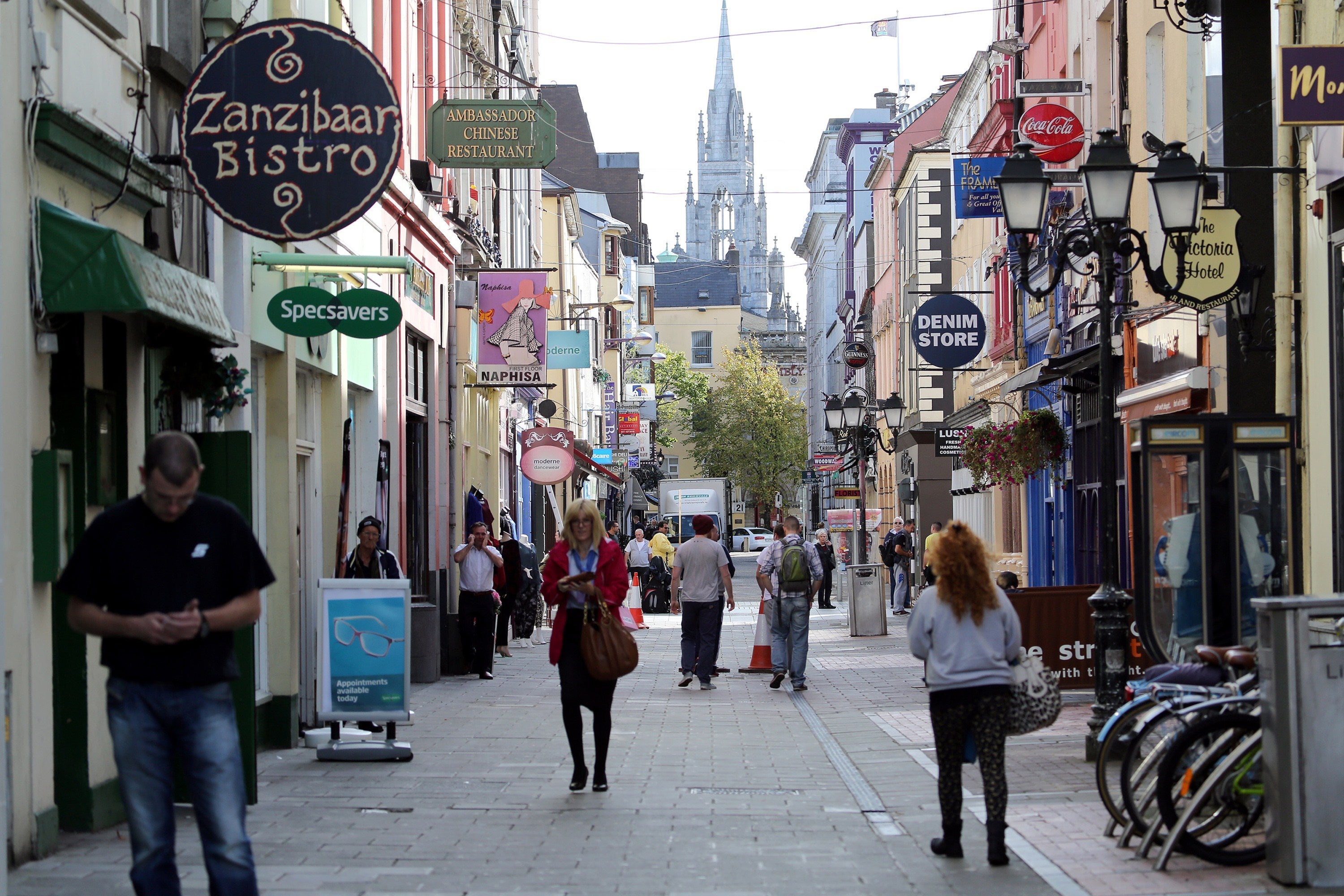 TO GO WITH AN AFP STORY BY CONOR BARRINS People walk through the streets in Cork city centre, southern Ireland on October 2, 2014. Perched on top of a hill overlooking the Irish city of Cork, surrounded by a dated industrial estate, Apple's European headquarters is an unlikely base for the world tech giant -- now under growing scrutiny over its local tax arrangements. The company has been in Cork since 1980 but the European Commission's suggestion that its tax deal with Ireland may amount to illegal state aid has drawn new attention on the Irish link for the makers of the iPhone and the iPad. AFP PHOTO / PAUL FAITH (Photo credit should read