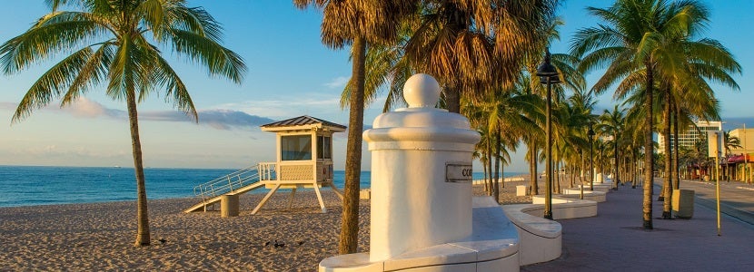 Fort Lauderdale beach at sunrise with lifeguard station and palm trees.