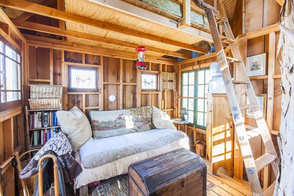 The living room has a small couch, while the bed is located in the loft. Image courtesy of Glamping Hub.