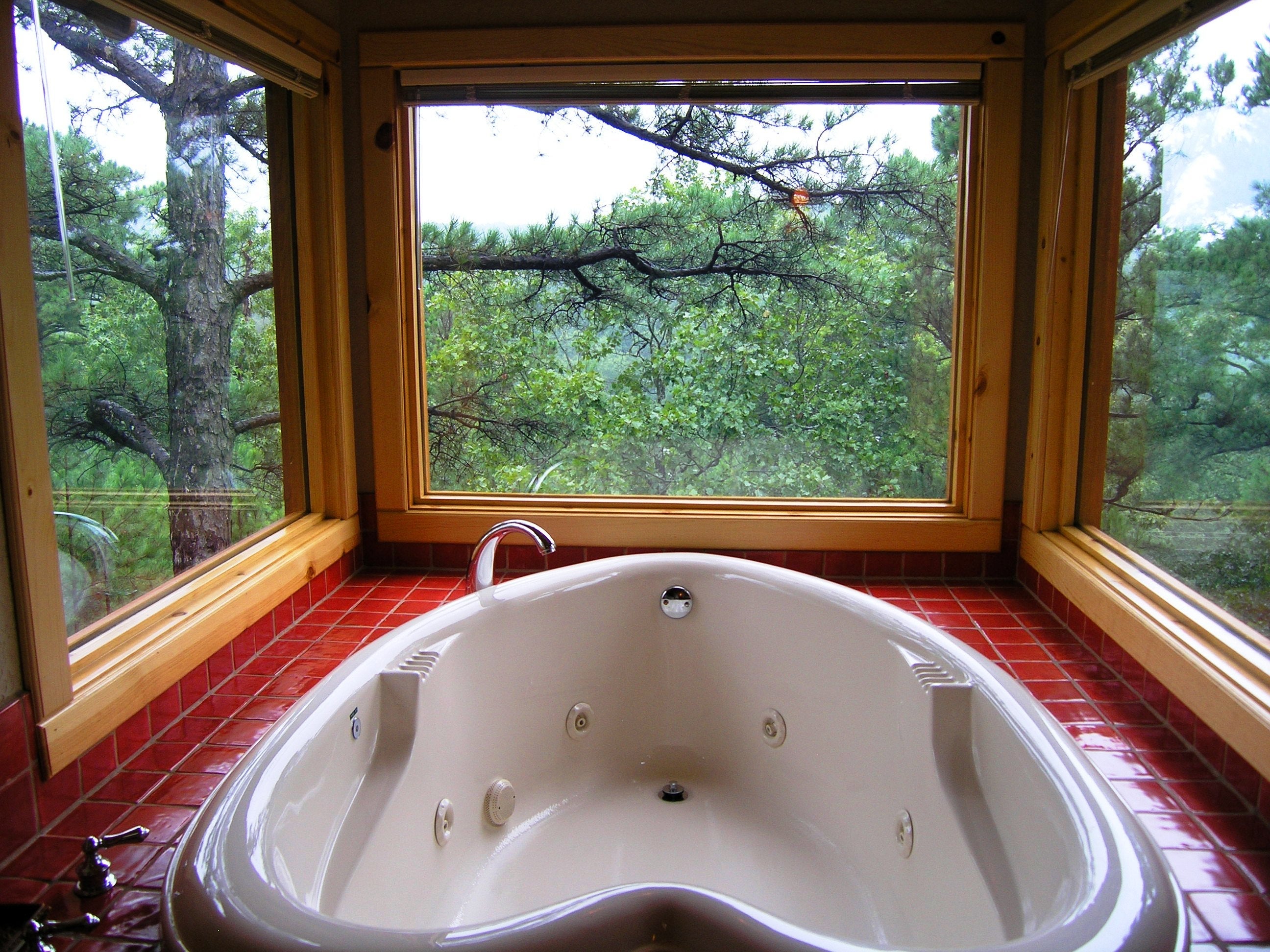 A double-size heart-shaped Jacuzzi is positioned in front three large windows. Photo courtesy of Laura at Tree House Cottages.