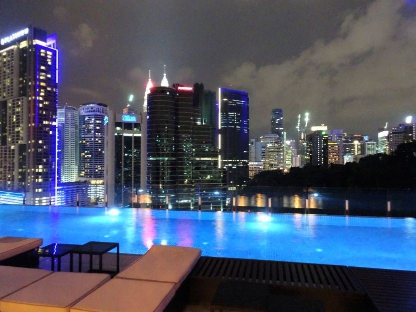 At night, the light from the pool glows beneath the tips of the Petronas Tower.