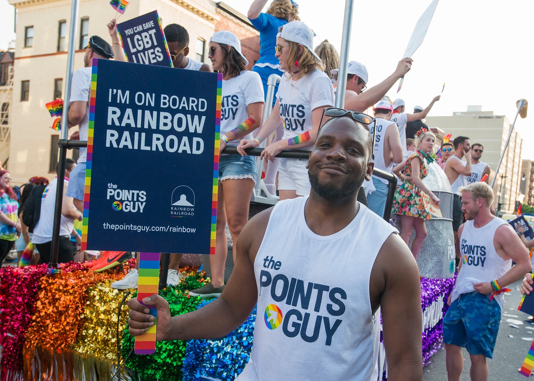 Photo of man holding sign during Pride Parade that reads "I'm on board Rainbow Railroad".
