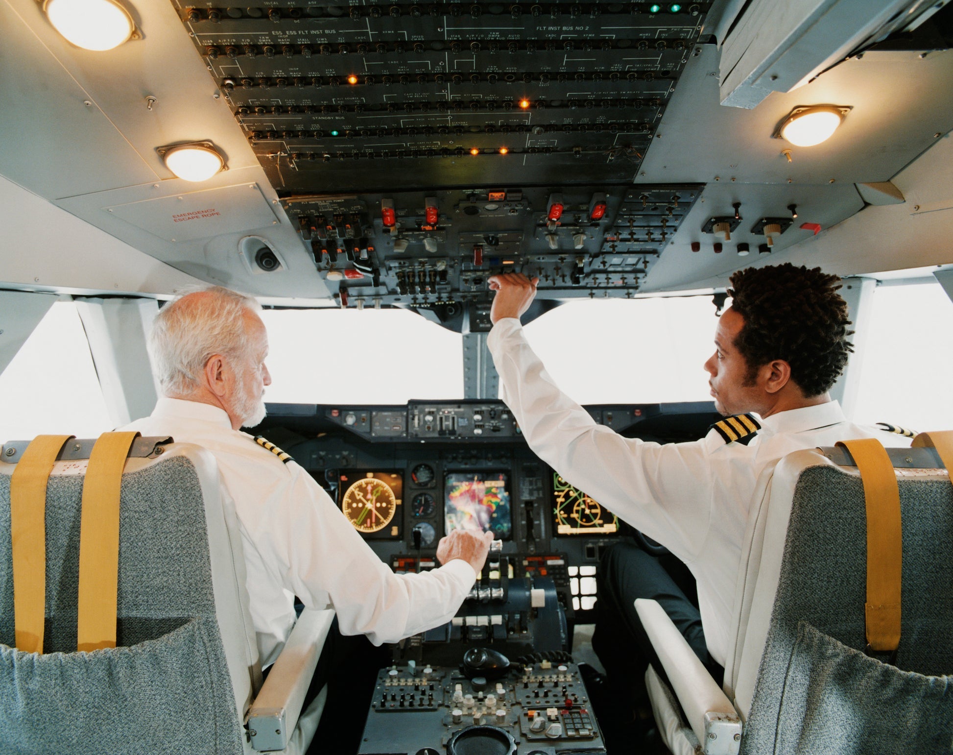 Portrait of Pilots Sitting in the Cockpit, Adjusting the Controls. Image by Digital Vision / Getty Images.