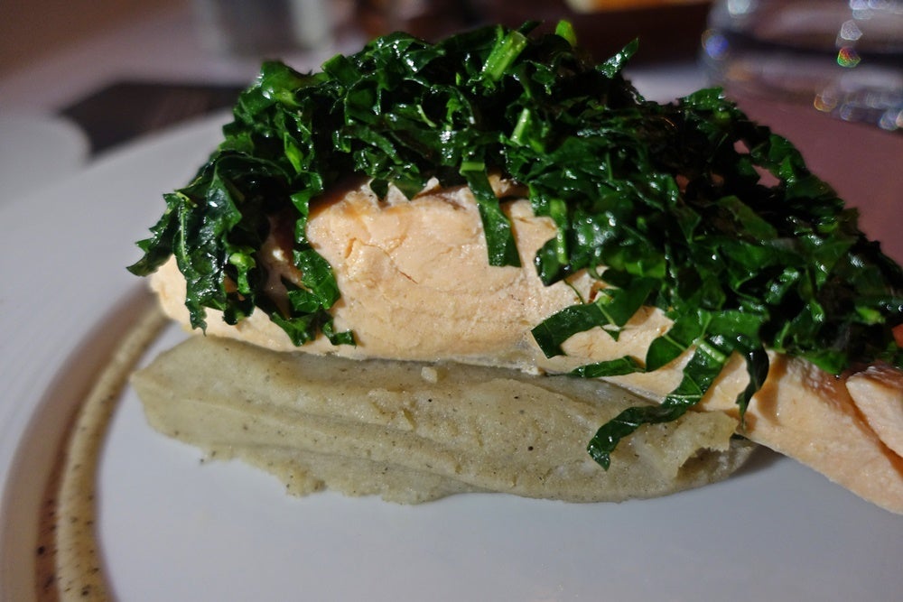 Salmon topped with kale over potatoes.