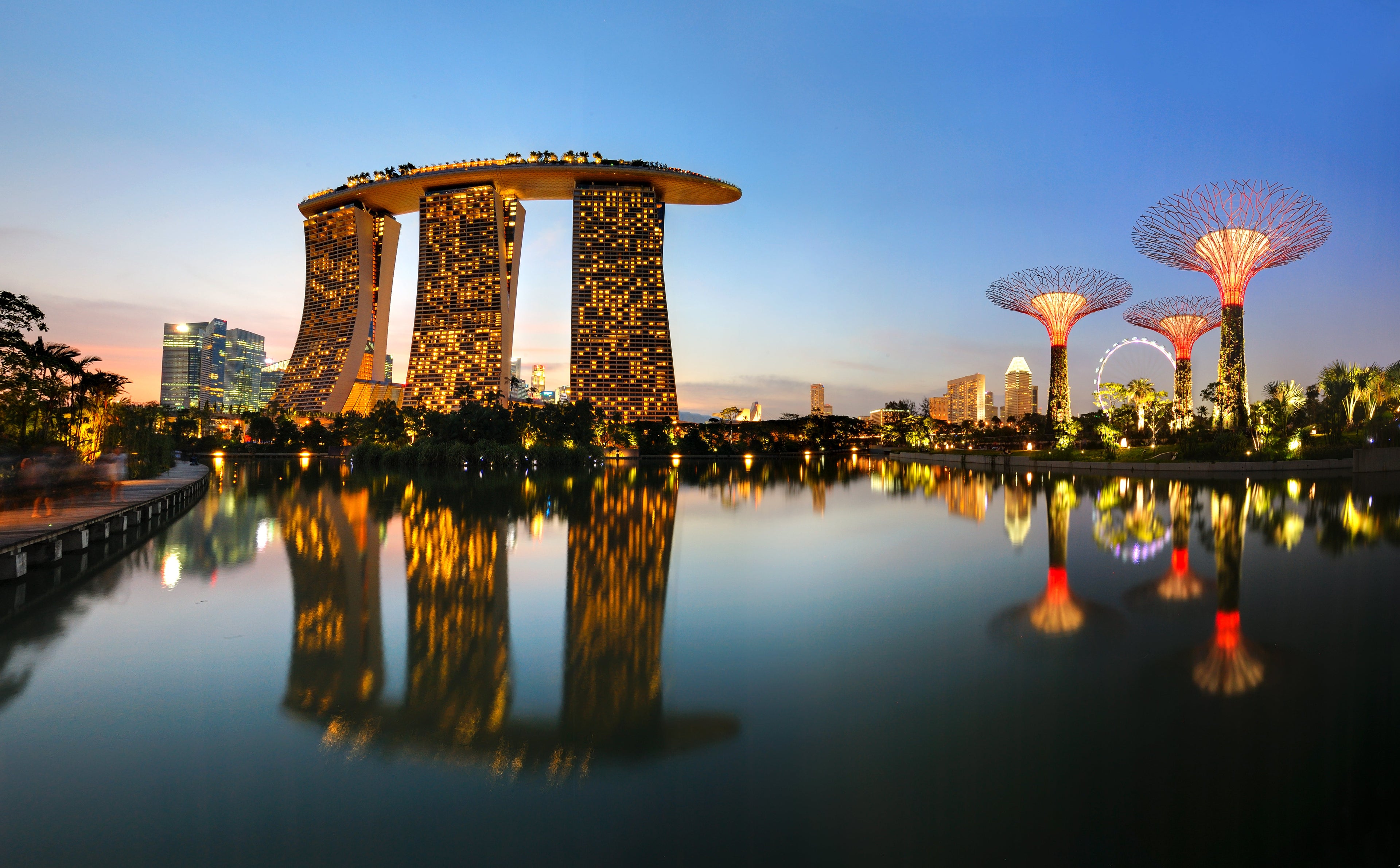 Gardens By The Bay and Marina Bay Sands reflection in water.