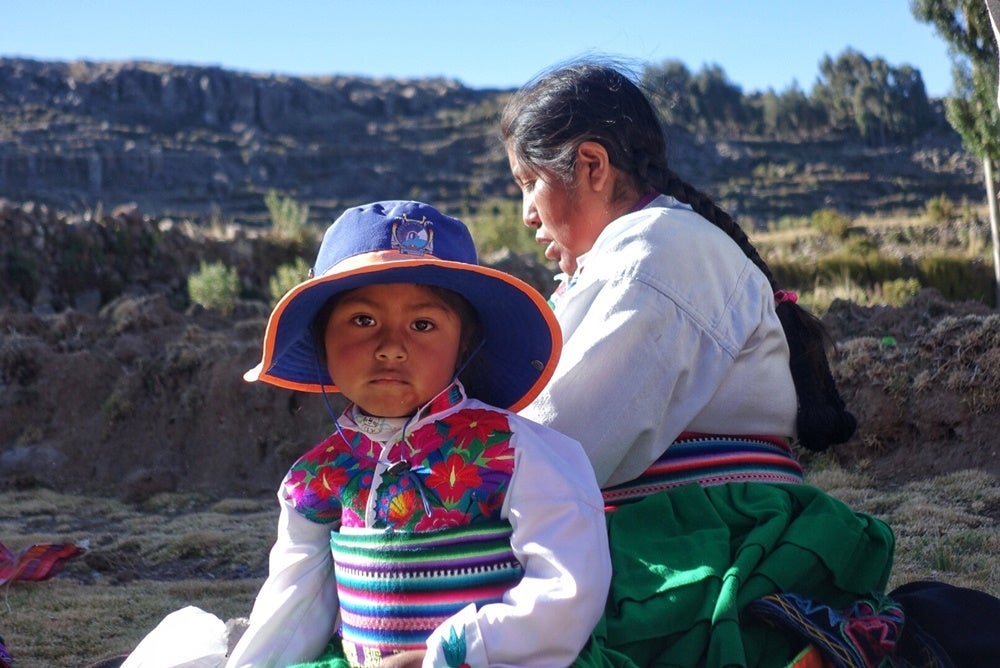 A mother weaves next to her inquisitive daughter in Amanpuri, an island in Lake Titicaca.