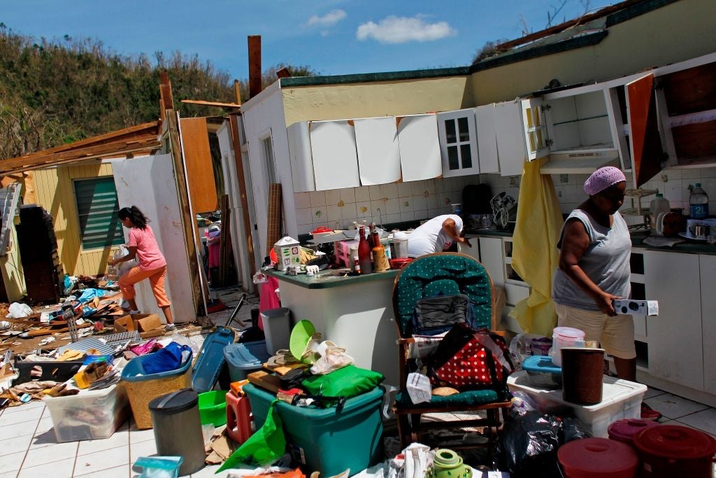 TOPSHOT - Family members collect belongings after hurricane force winds destroyed their house in Toa Baja, west of San Juan, Puerto Rico, on September 24, 2017 following the passage of Hurricane Maria.Authorities in Puerto Rico rushed on September 23, 2017 to evacuate people living downriver from a dam said to be in danger of collapsing because of flooding from Hurricane Maria. / AFP PHOTO / Ricardo ARDUENGO (Photo credit should read RICARDO ARDUENGO/AFP/Getty Images)