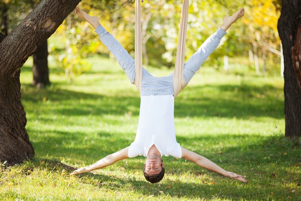 Anti-gravity Yoga, man doing yoga exercises in the park