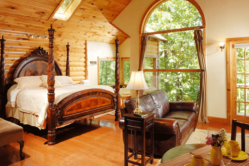 Elegant wood furniture fills the bedroom of this treehouse. Image courtesy of Laura at Treehouse Cottages.