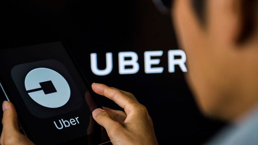 Young man holds a smart device while using Uber app