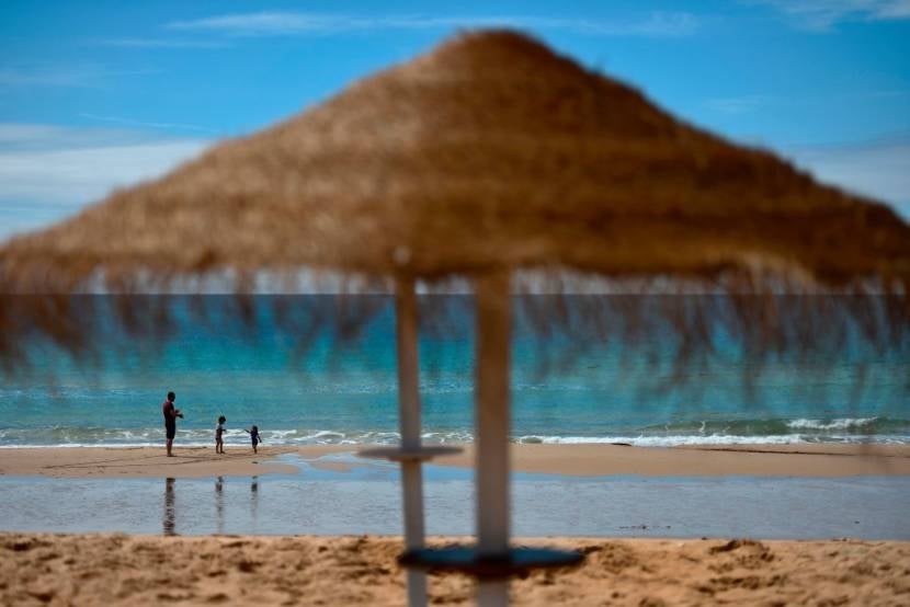 A man and two children stand on the beach in Praia da Luz in Algarve, southern Portugal, on April 28, 2017.Scarred by Madeleine McCann's disappearance 10 years ago, the seaside resort town of Praia da Luz in southern Portugal is struggling to shake off the mystery of the young British girl's disappearance. Madeleine McCann (Maddie) disappeared on May 3, 2007. Portuguese police closed the case in 2008 before reopening it five years later. / AFP PHOTO / PATRICIA DE MELO MOREIRA (Photo credit should read PATRICIA DE MELO MOREIRA/AFP/Getty Images)