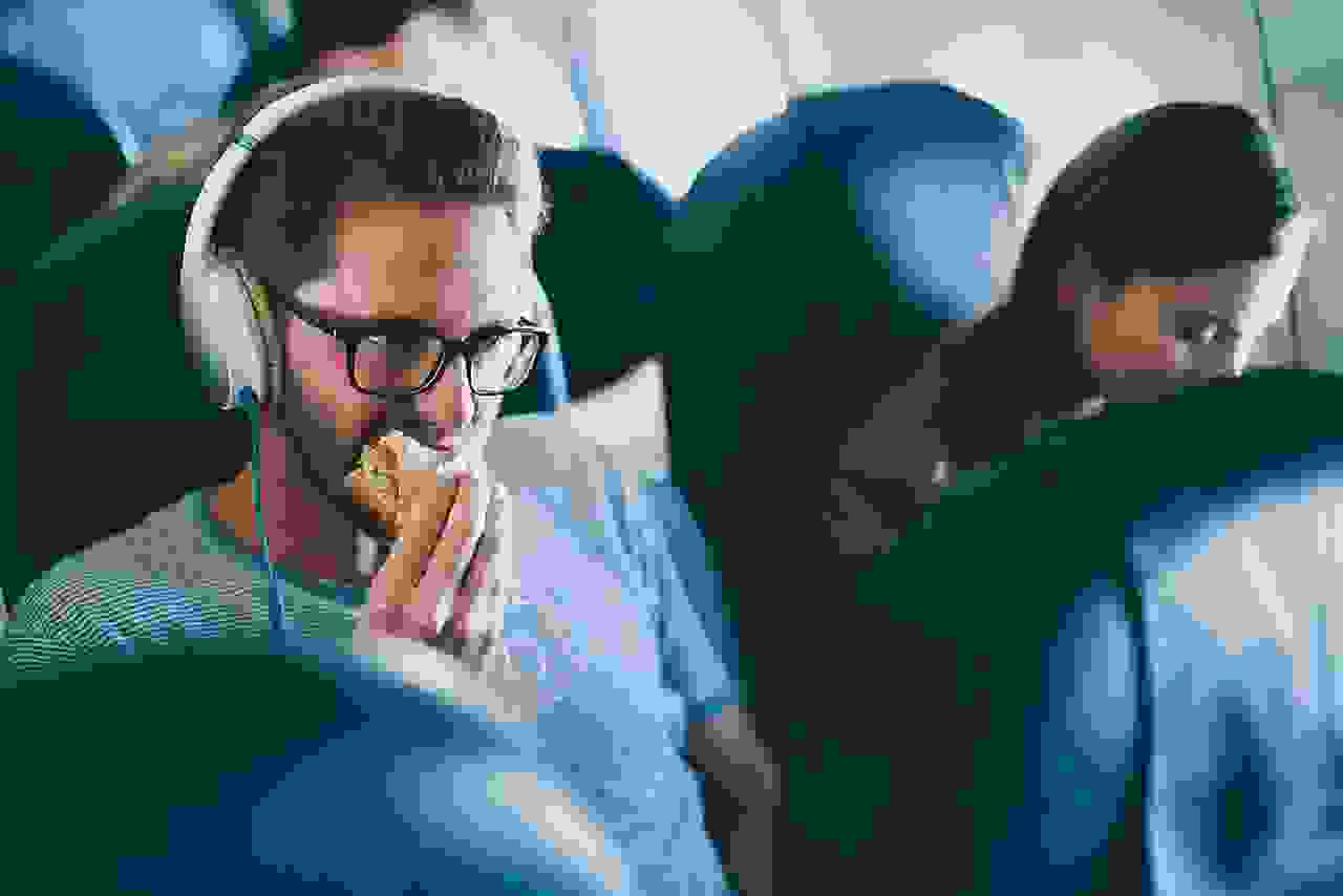 Man eating sandwich in economy class in airplane. (Photo by amriphoto/Getty Images)