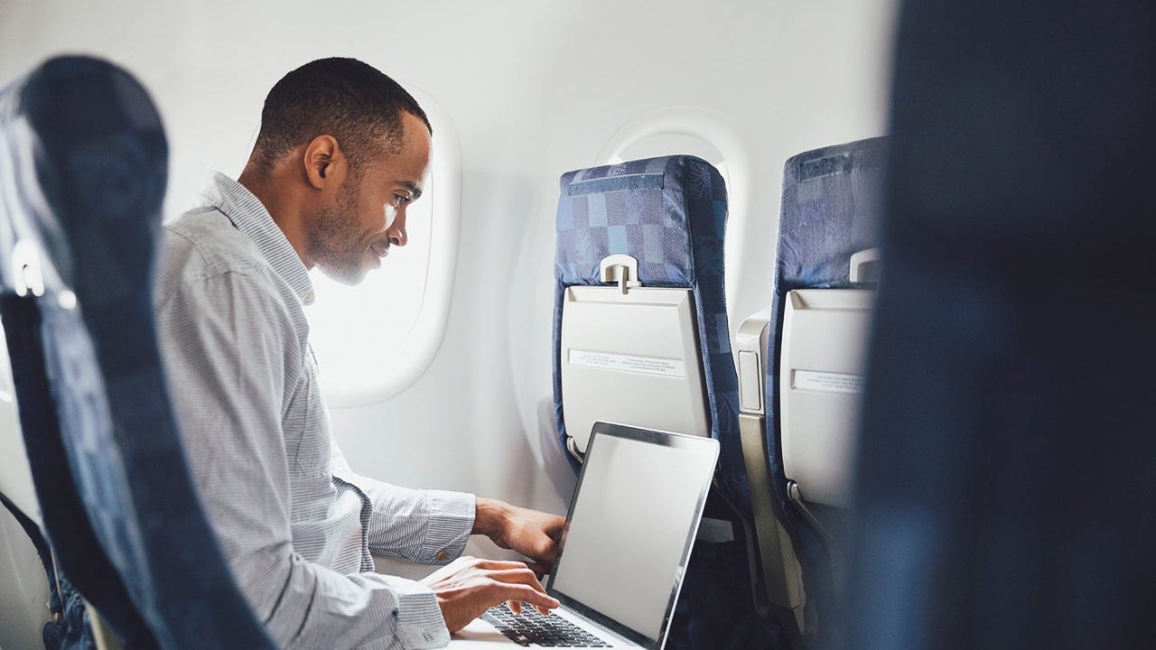 Man using laptop in airplane