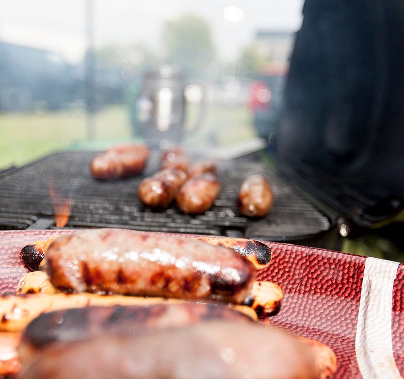 Tailgate scene, cooking hot dogs and sausages on the grill