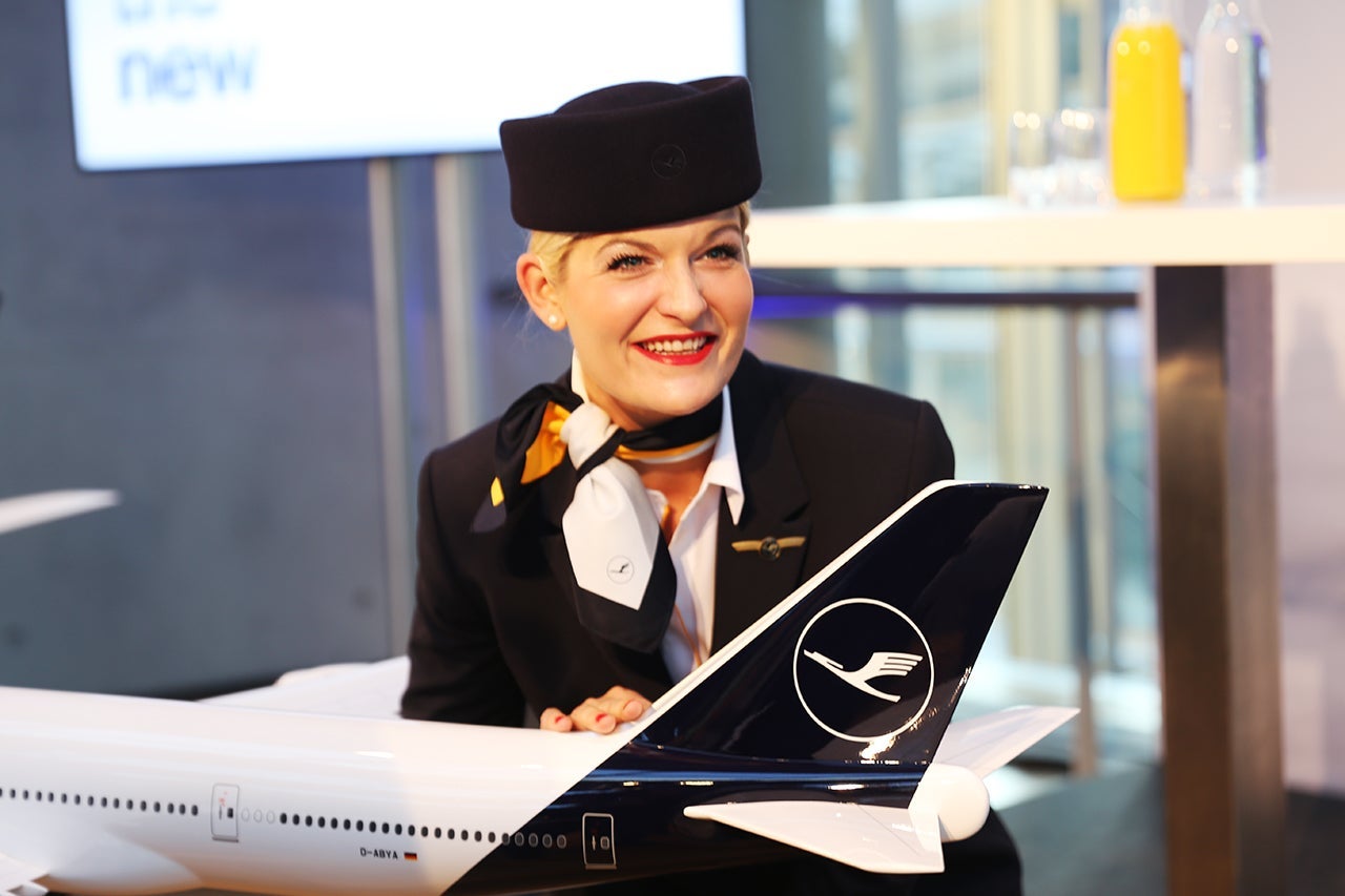 A Lufthansa flight attendant poses with a model of the carrier's new livery. Image by Brendan Dorsey / The Points Guy.