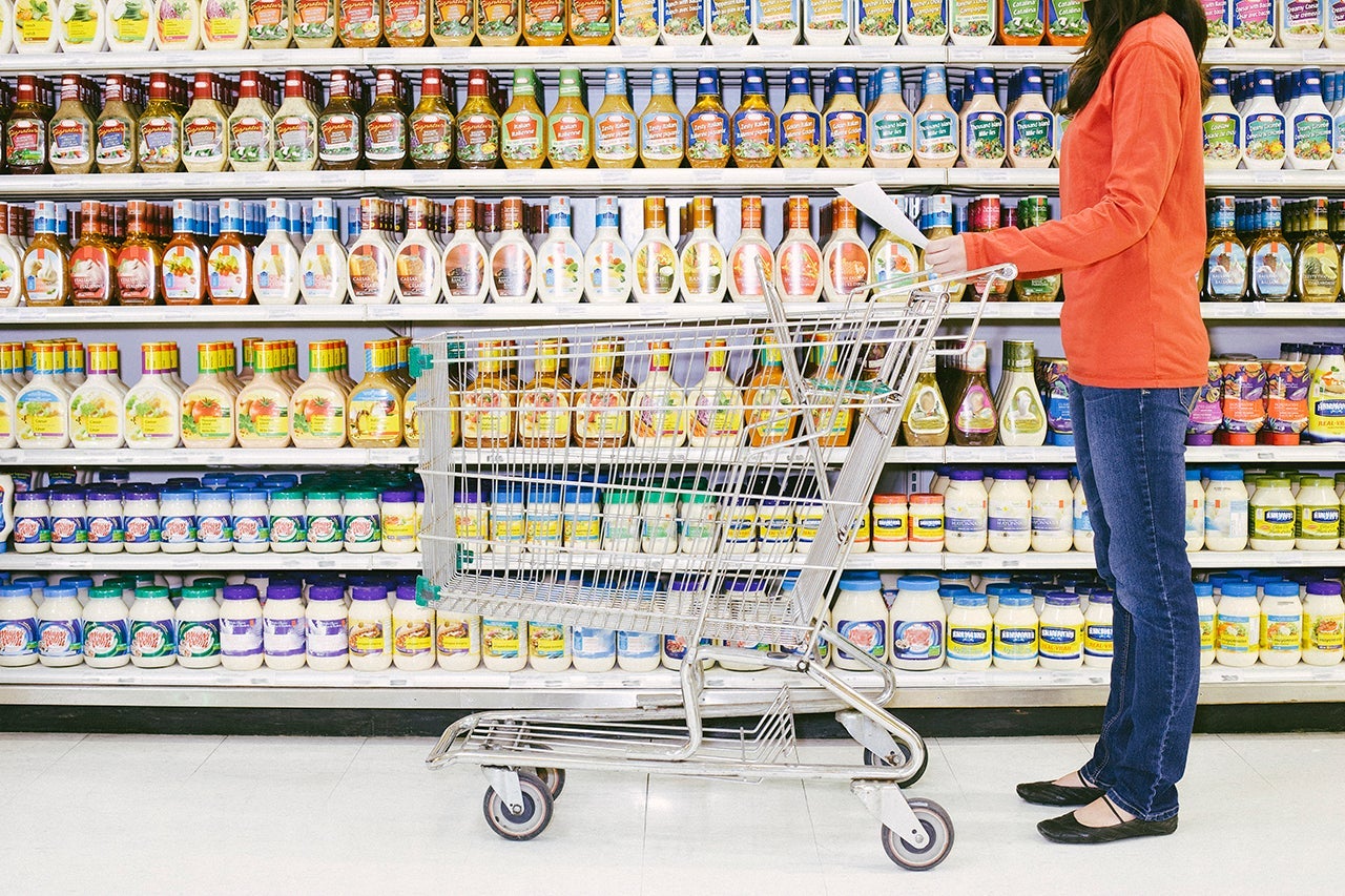 A person with a shopping cart pauses to look at items in a supermarket