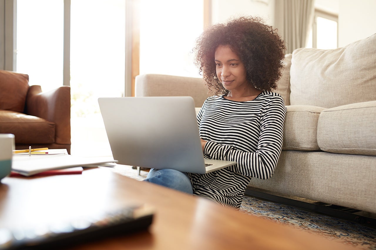 Shot of a young woman relaxing with her laptop at home. (Photo by Squaredpixels/Getty Images)