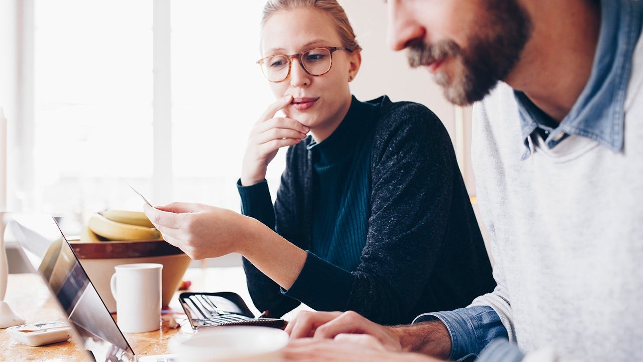 Side view of couple shopping online from laptop at home