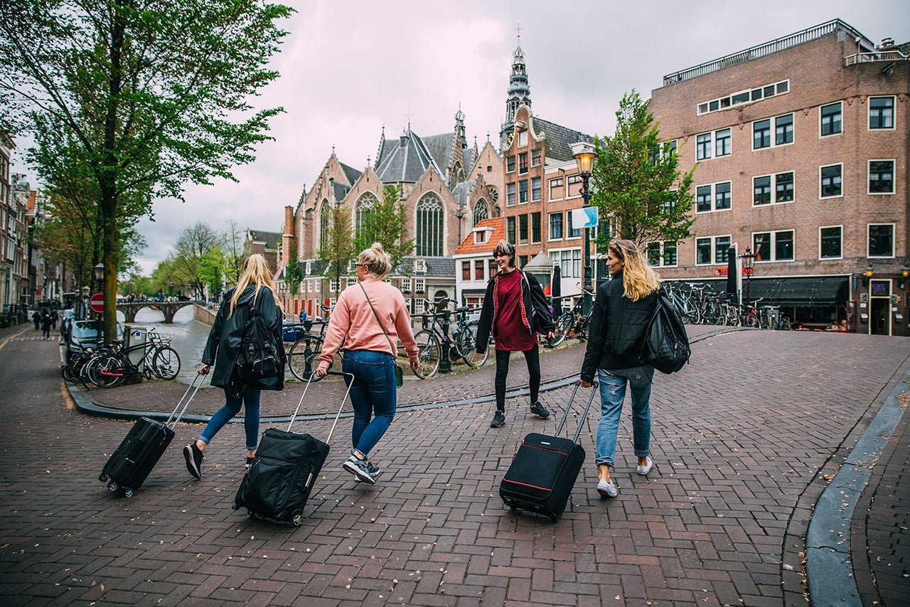 travelers with suitcases walk on a brick street