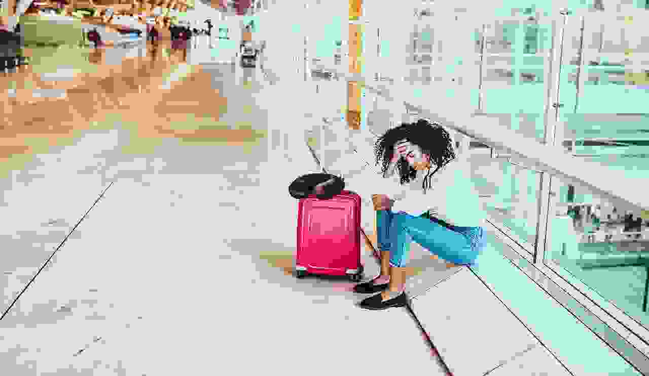 Woman sad and unhappy at the airport with flight canceled. (Photo by David-Prado/Getty Images)