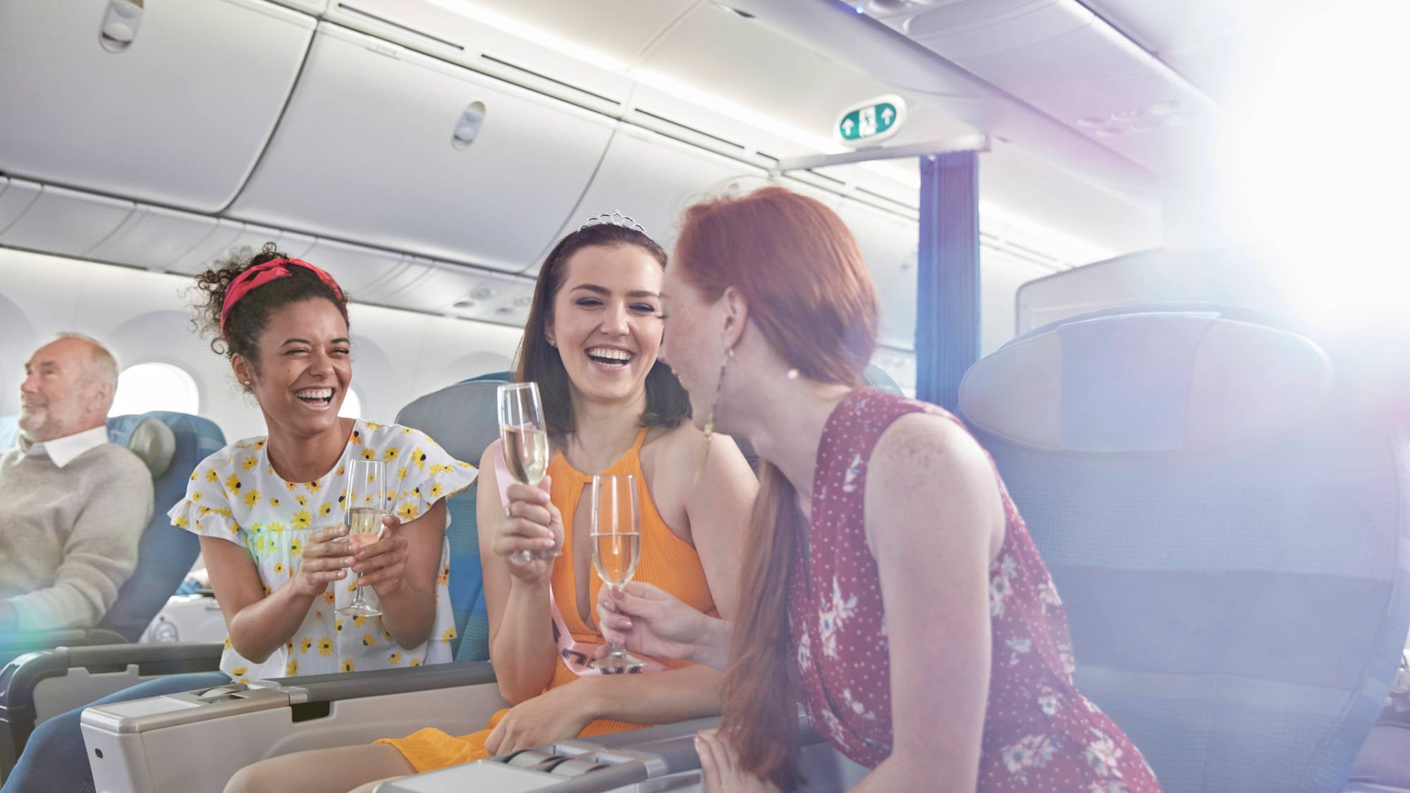 Young women friends drinking champagne in first class on airplane