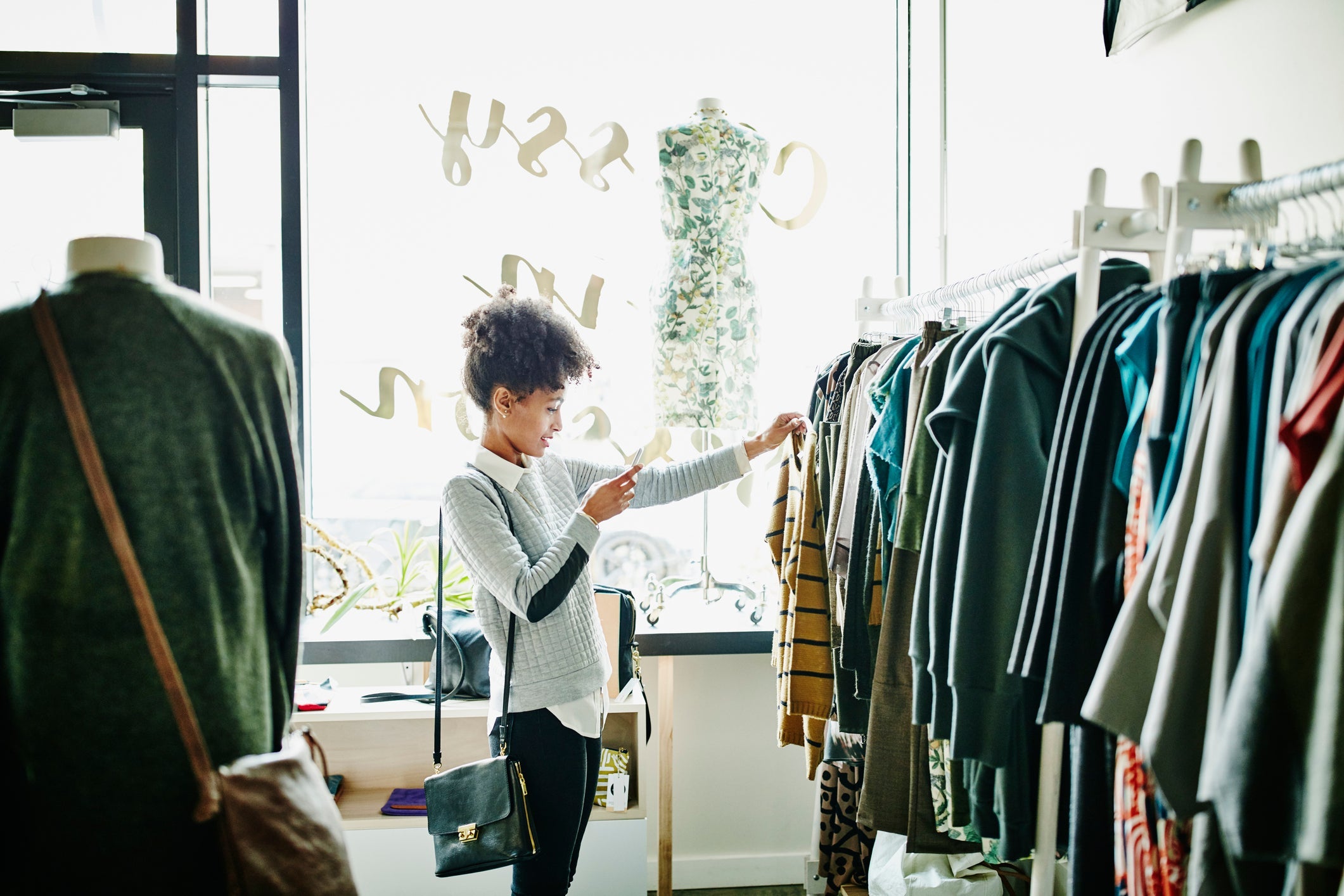 A Person examines a rack of clothing for sale in a store