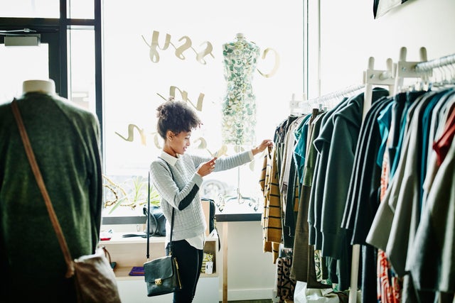 A Person examines a rack of clothing for sale in a store