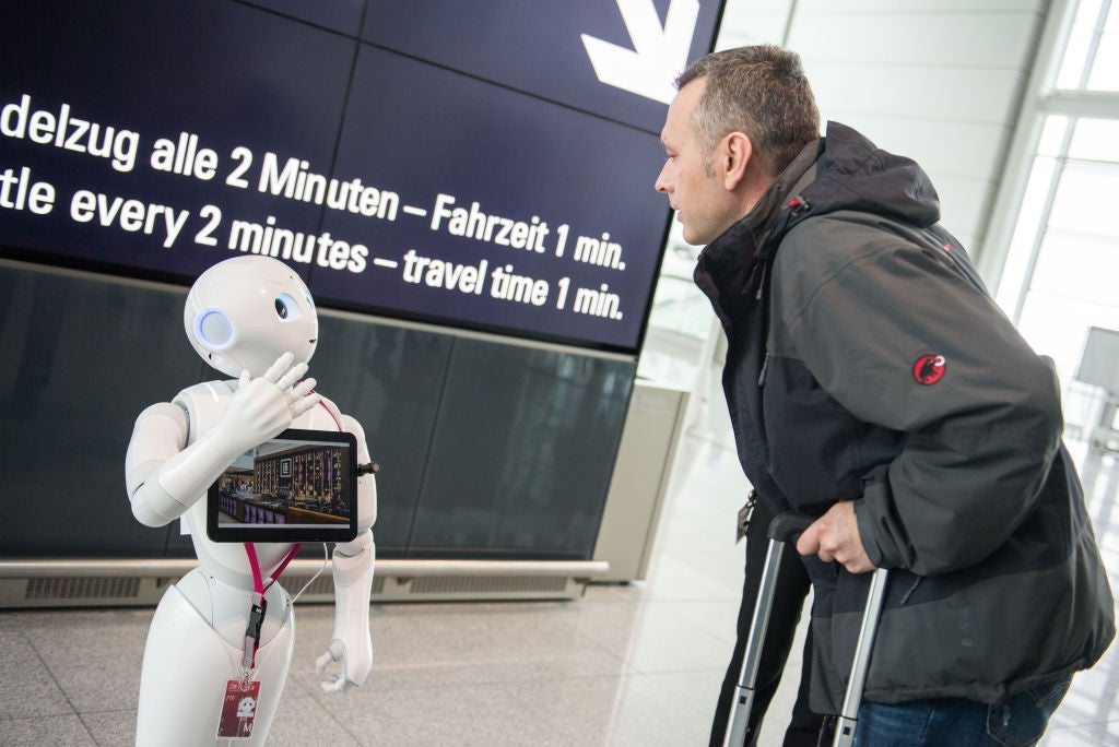 Robot Josie Pepper assists passengers travelling from the airport in Munich, Germany, 20 February 2018. Pepper is a humanoid robot programmed to analyse and emulate human gestures and facial expressions. Photo: Lino Mirgeler/dpa (Photo by Lino Mirgeler/picture alliance via Getty Images)