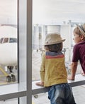 Two children wearing straw hats looking through window to airplane on the apron