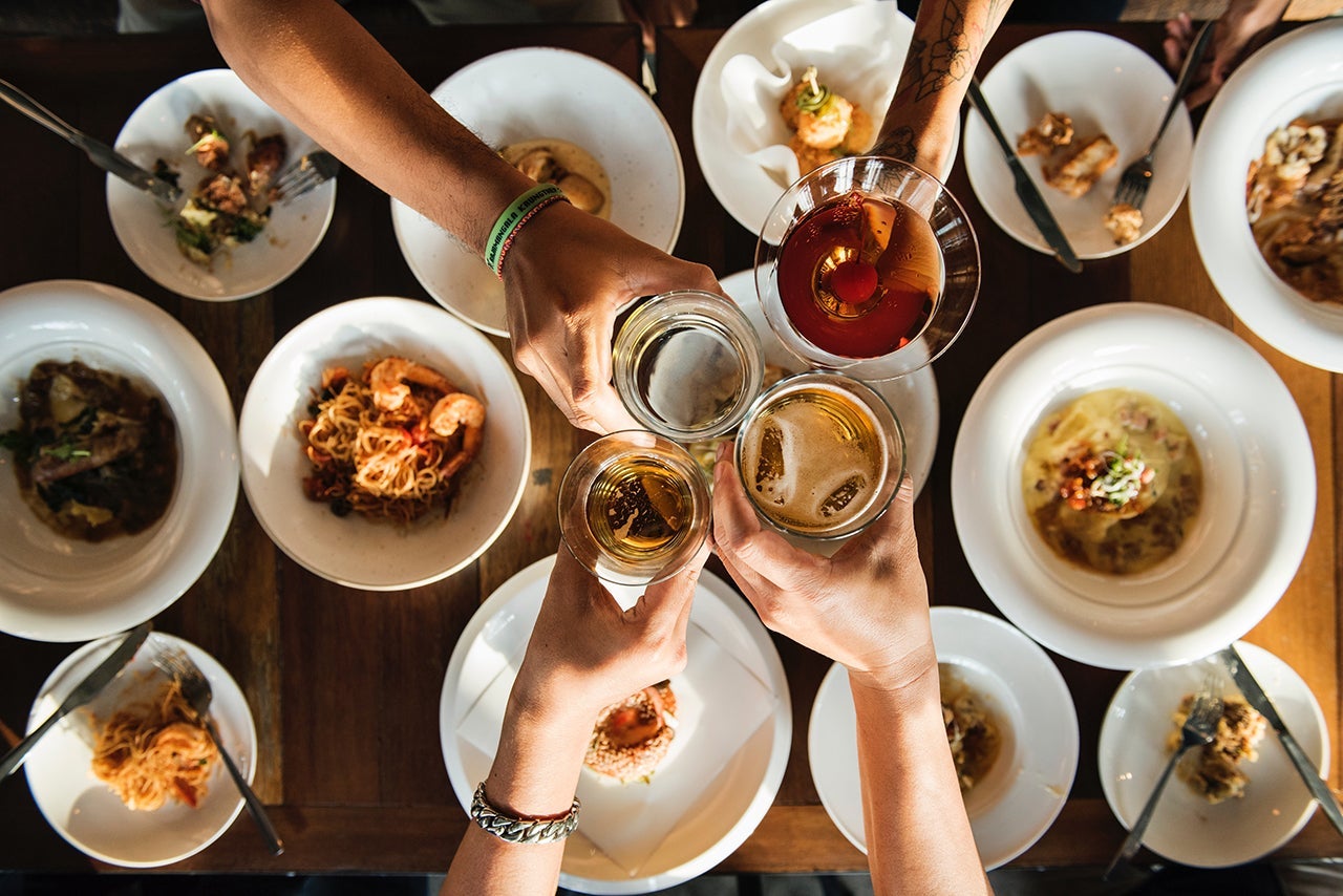 an overhead view of a table set with food and hands holding drinks