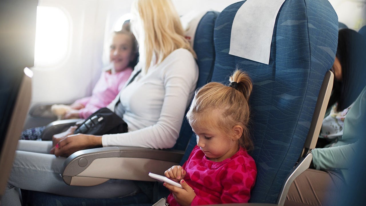 Little girl using smart phone in airplane.