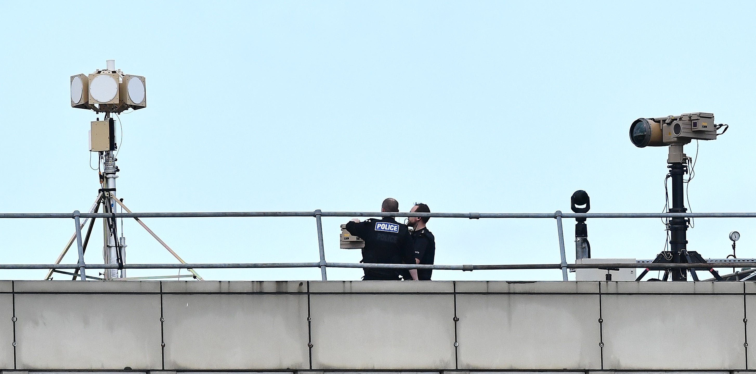 Police officers stand near equipment on the rooftop of a building at London Gatwick Airport, south of London, on December 21, 2018, as flights resumed following the closing of the airfield due to a drones flying. - British police were Friday considering shooting down the drone that has grounded flights and caused chaos at London's Gatwick Airport, with passengers set to face a third day of disruption. Police said it was a "tactical option" after more than 50 sightings of the device near the airfield since Wednesday night when the runway was first closed. (Photo by Ben STANSALL / AFP) (Photo credit should read BEN STANSALL/AFP/Getty Images)