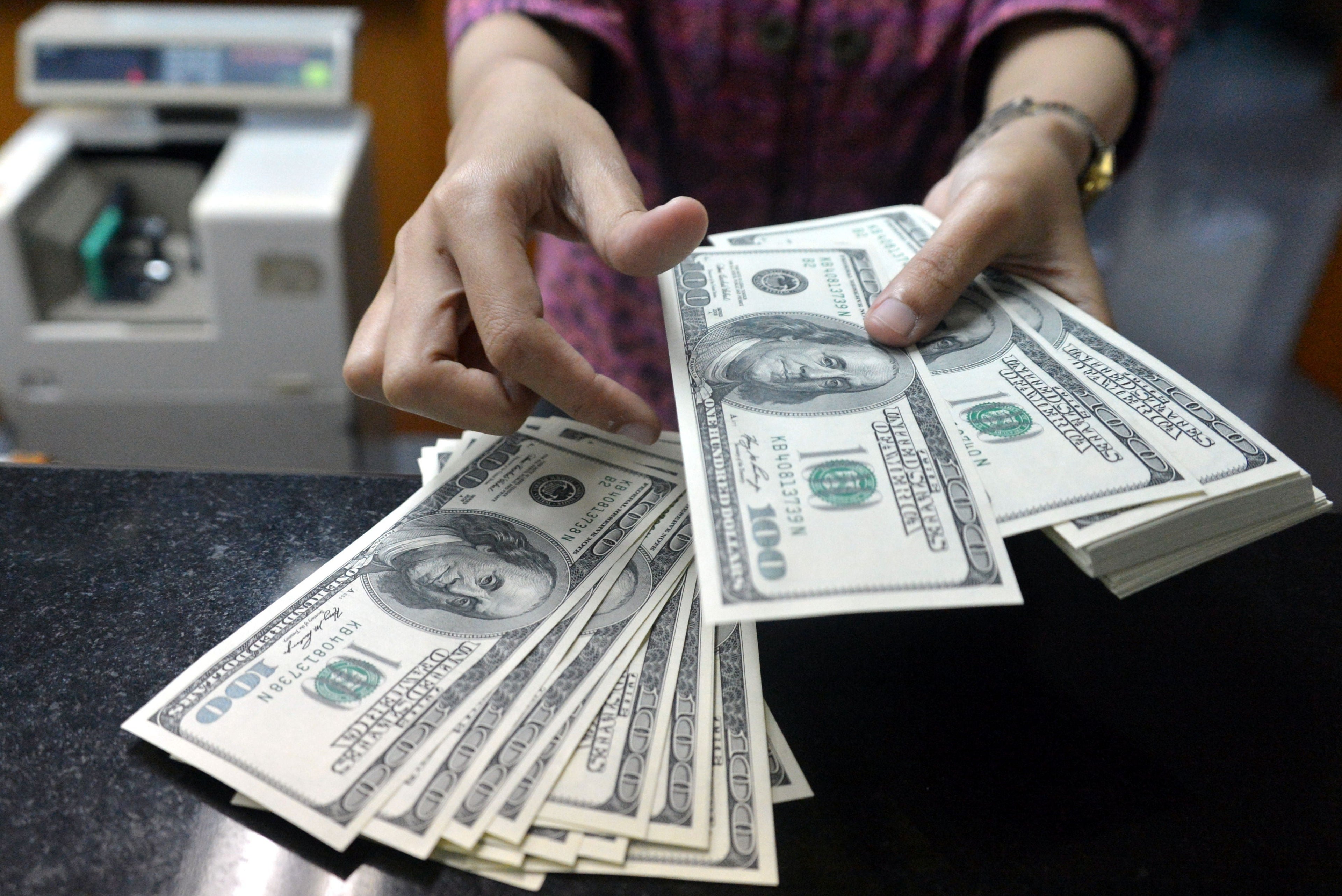 An employee counts USD notes at a money change outlet