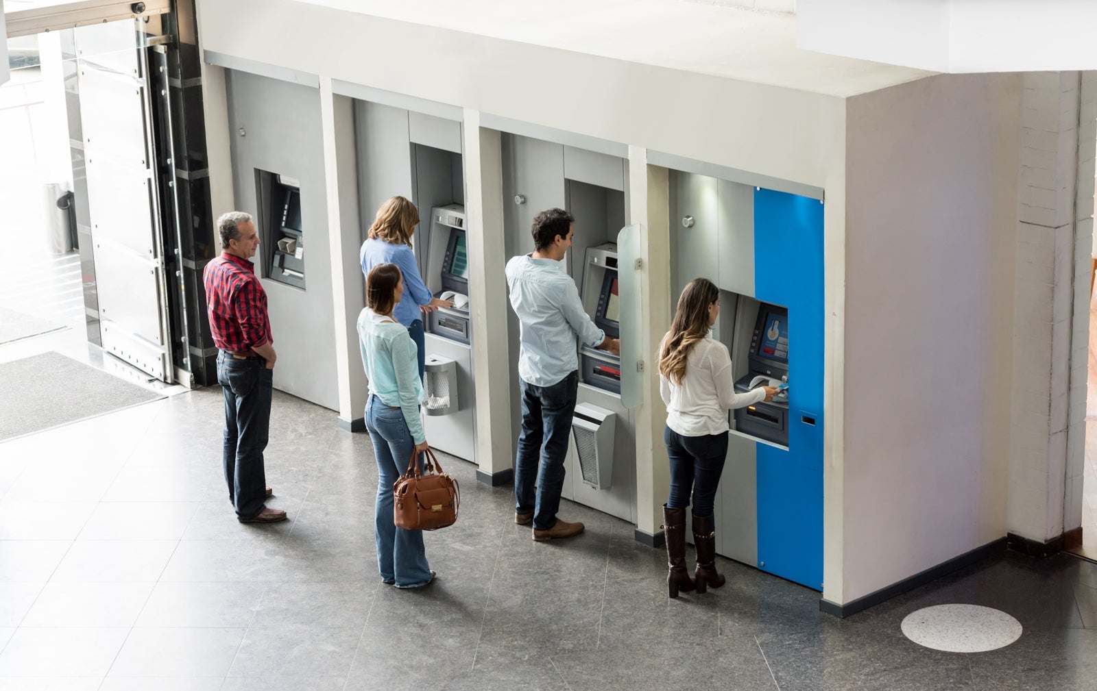 Group of Latin American people withdrawing cash at an ATM